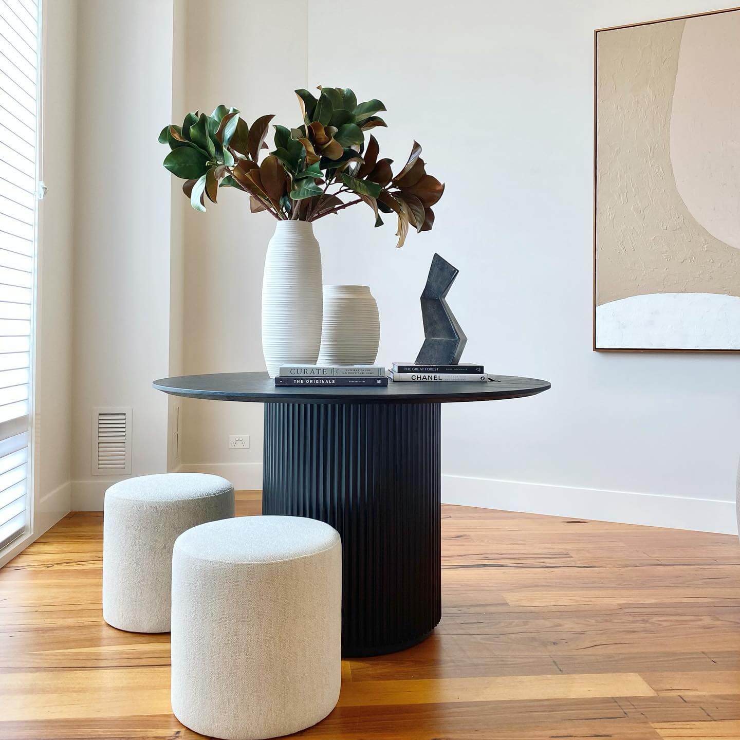 Dark Fluted Pedestal Table With Sculptural Art and Tall Greenery