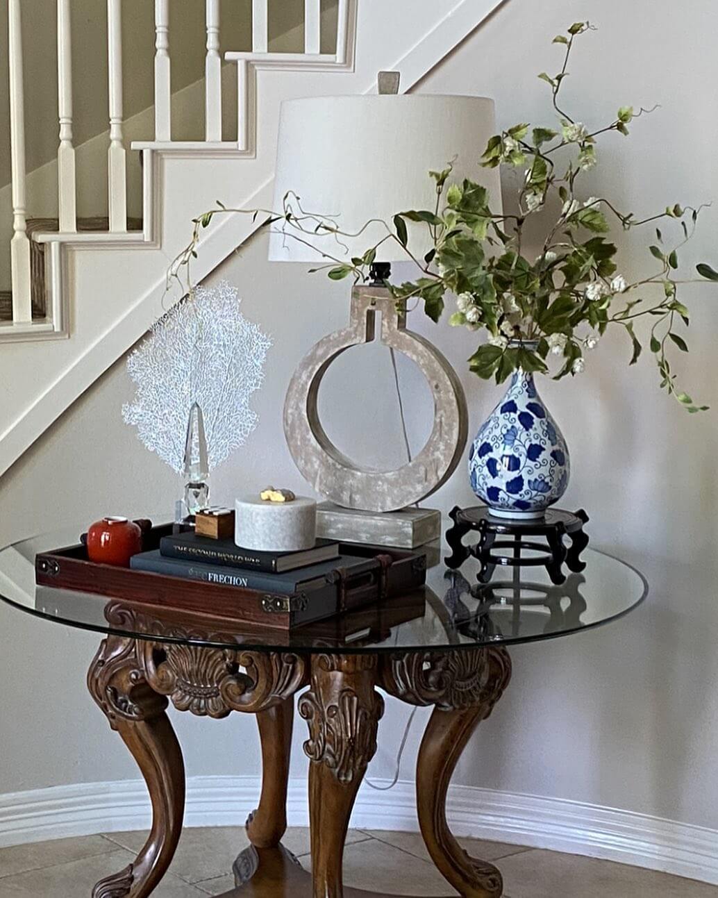 Glass Top Table with Carved Wood Base and Layered Decor