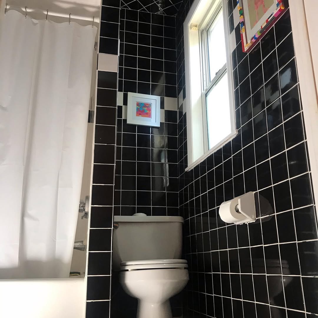 Framed Art Adds Color To Black Tiled Bathroom Walls