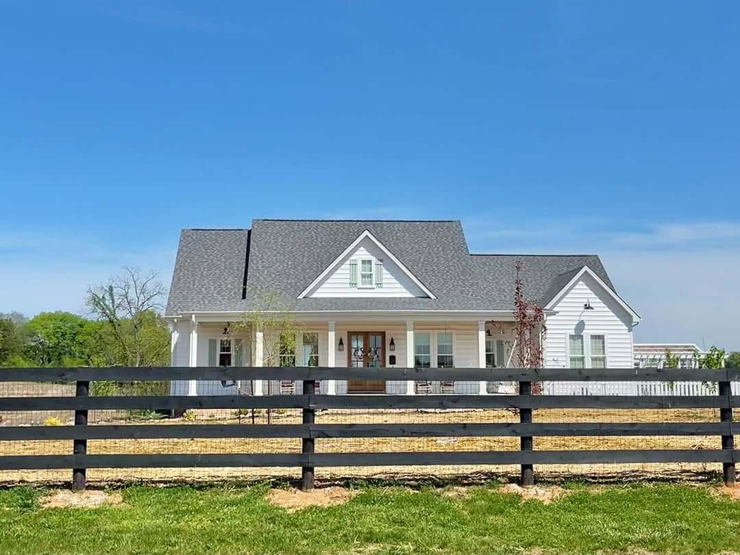 Wide Black Fence Defines the Farmhouse Property
