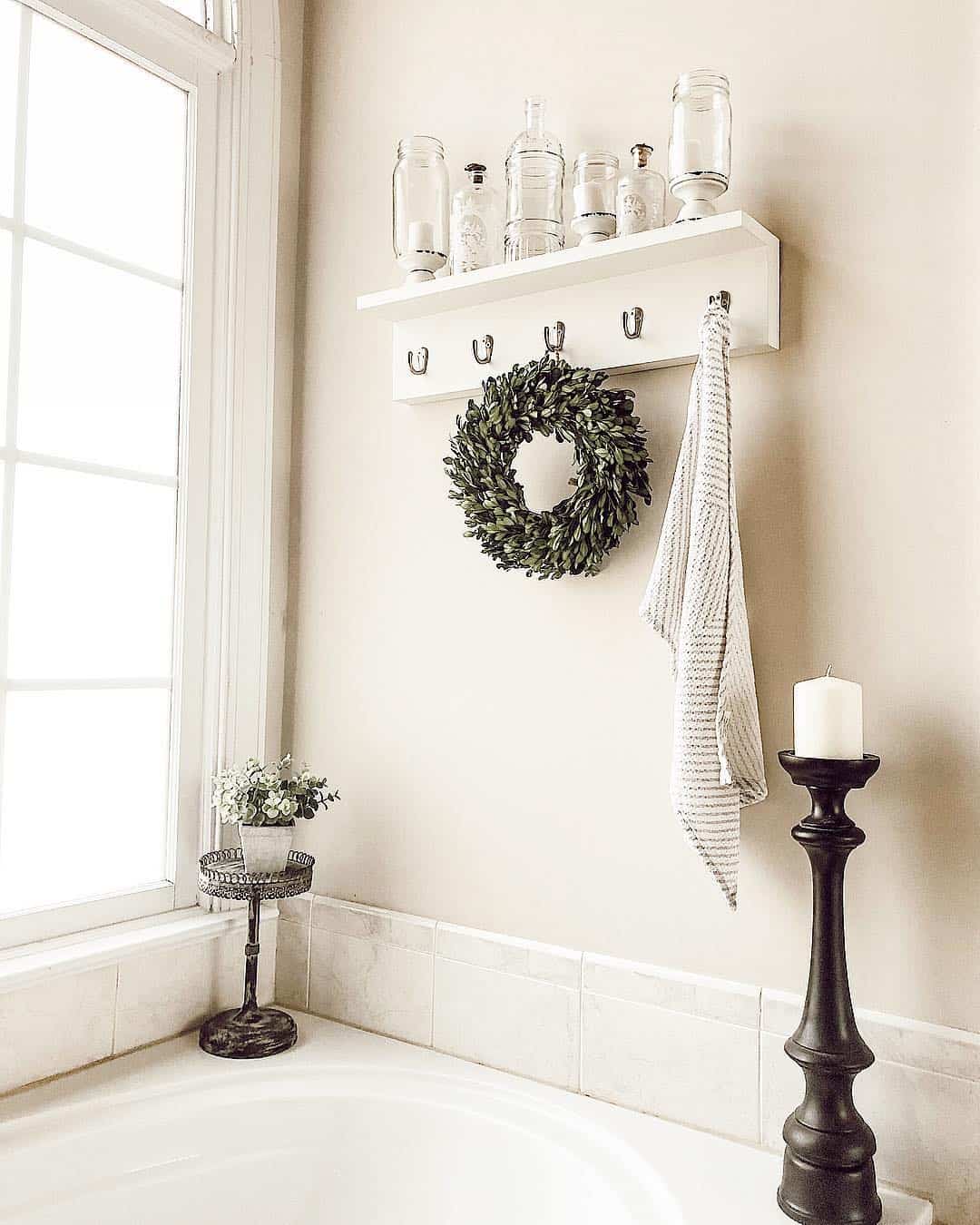 White Shelf With Hooks Displays Jars and a Boxwood Wreath