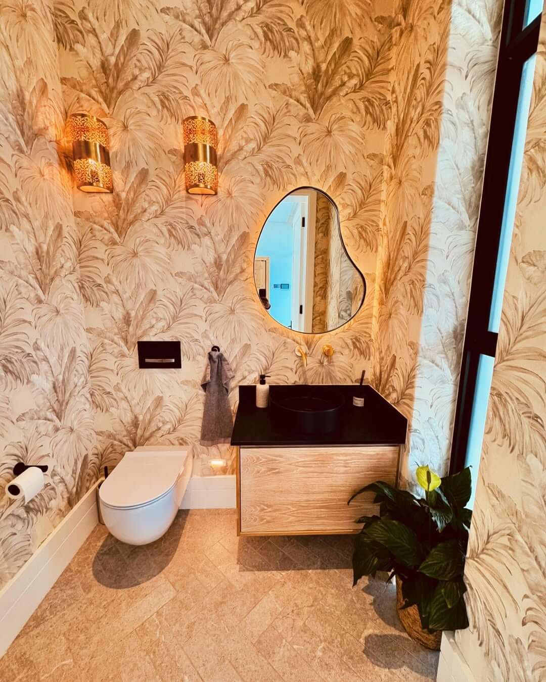 Ornate Brass Sconces Illuminate Tropical Wallpaper