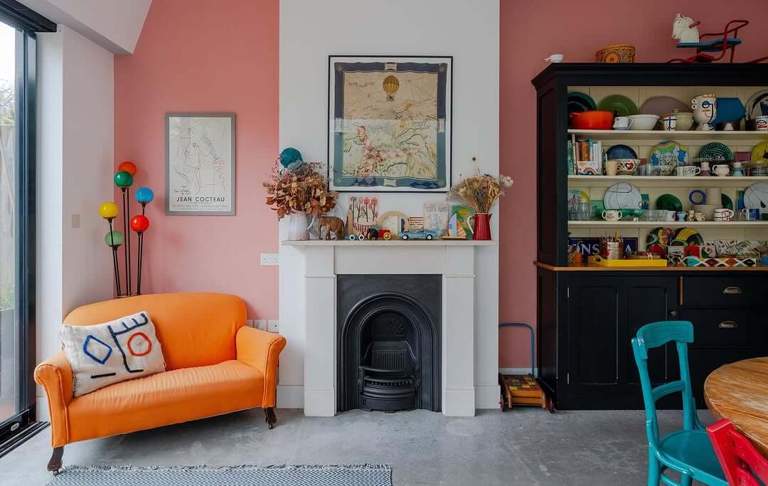 Pink walls create a cheerful backdrop for a bold orange sofa