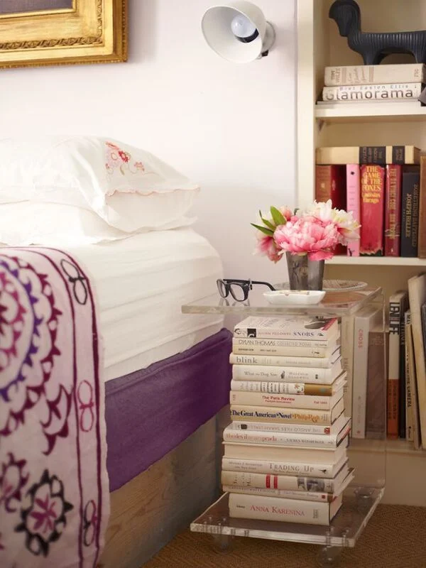 Clear Acrylic Pedestal Holds Stacked Books Beside Bed
