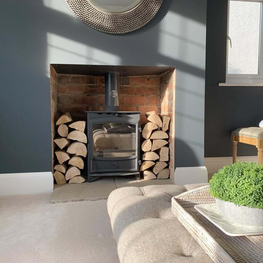 Neatly Stacked Logs Flank a Modern Wood-Burning Stove