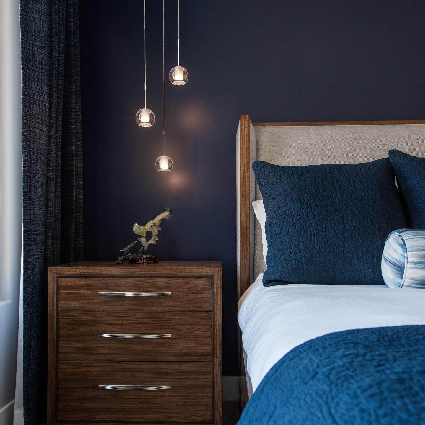 Glass Globe Pendants Add Soft Light Above Wooden Nightstand