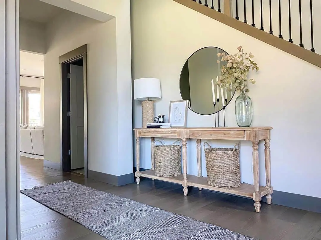 Round Mirror Reflects Entryway Decor with Tall Candlesticks