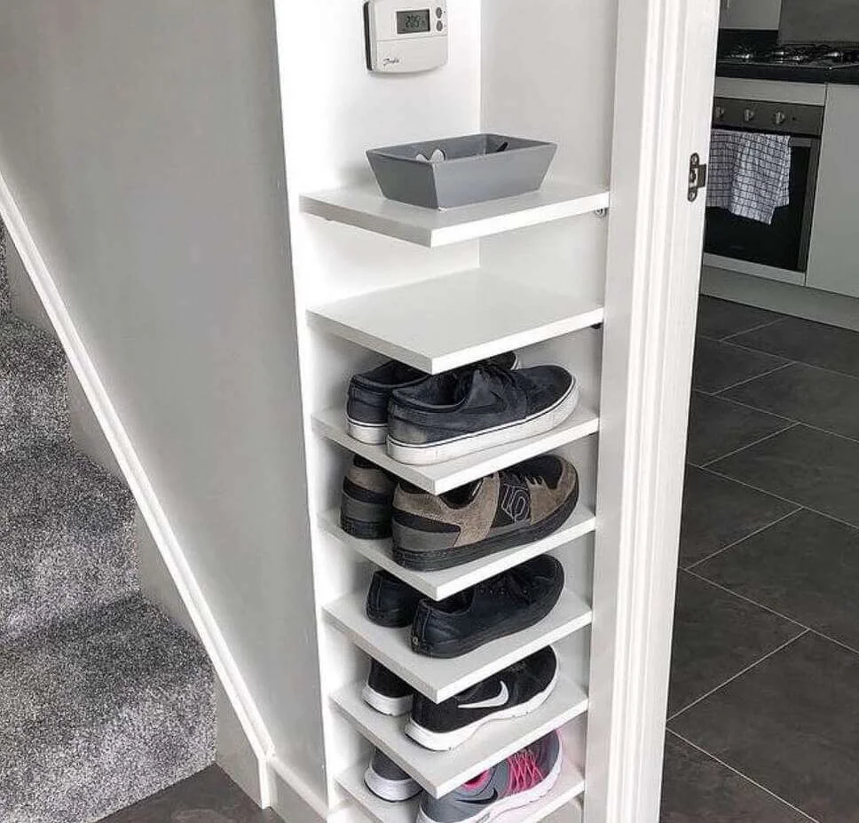 Narrow White Shelving Unit for Storing Shoes Next to Stairs