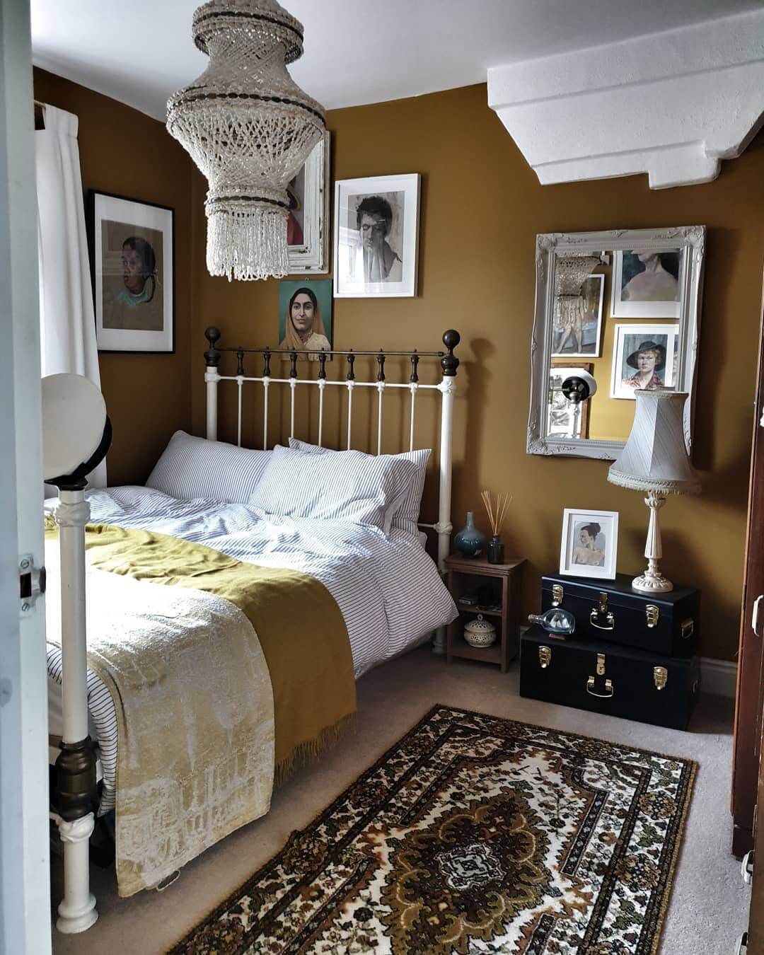 Layered portraits create a gallery wall above the bed