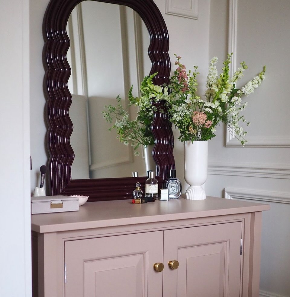 Frame a Delicate Vanity Display with a Wavy Dark Wood Mirror