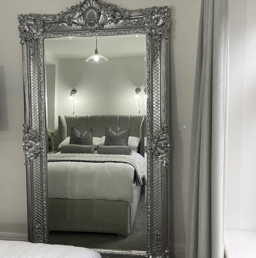 Reflect a Plush Tufted Bed with an Ornate Silver Floor Mirror