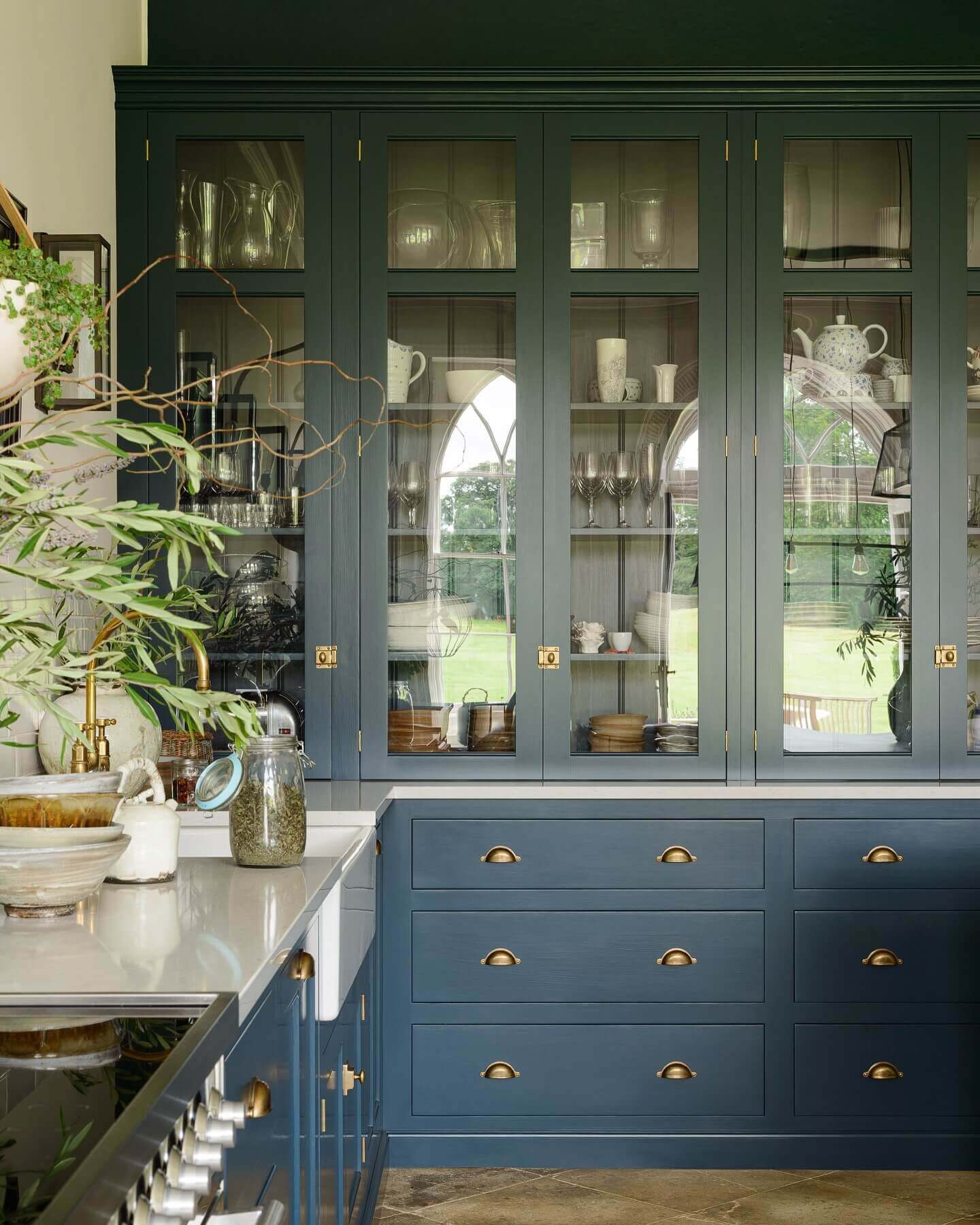 Glass-fronted blue cabinets display curated dishware