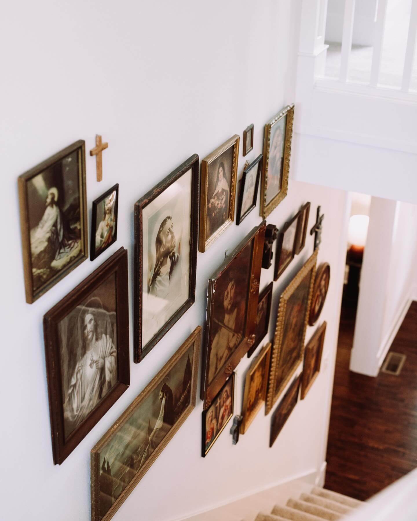 Gallery wall layers religious art with a wooden cross