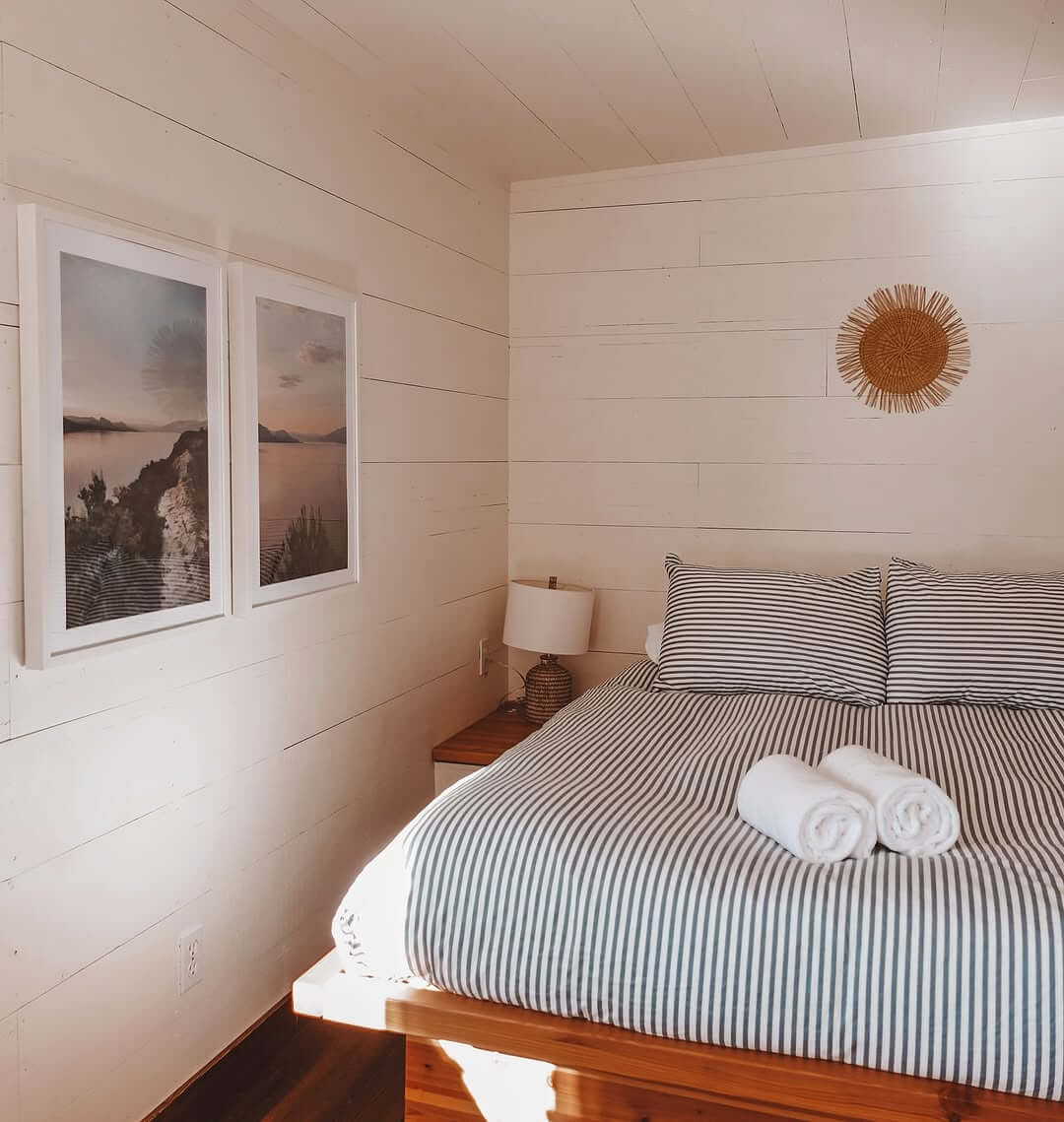 Pair of Framed Coastal Prints Above a Striped Bed