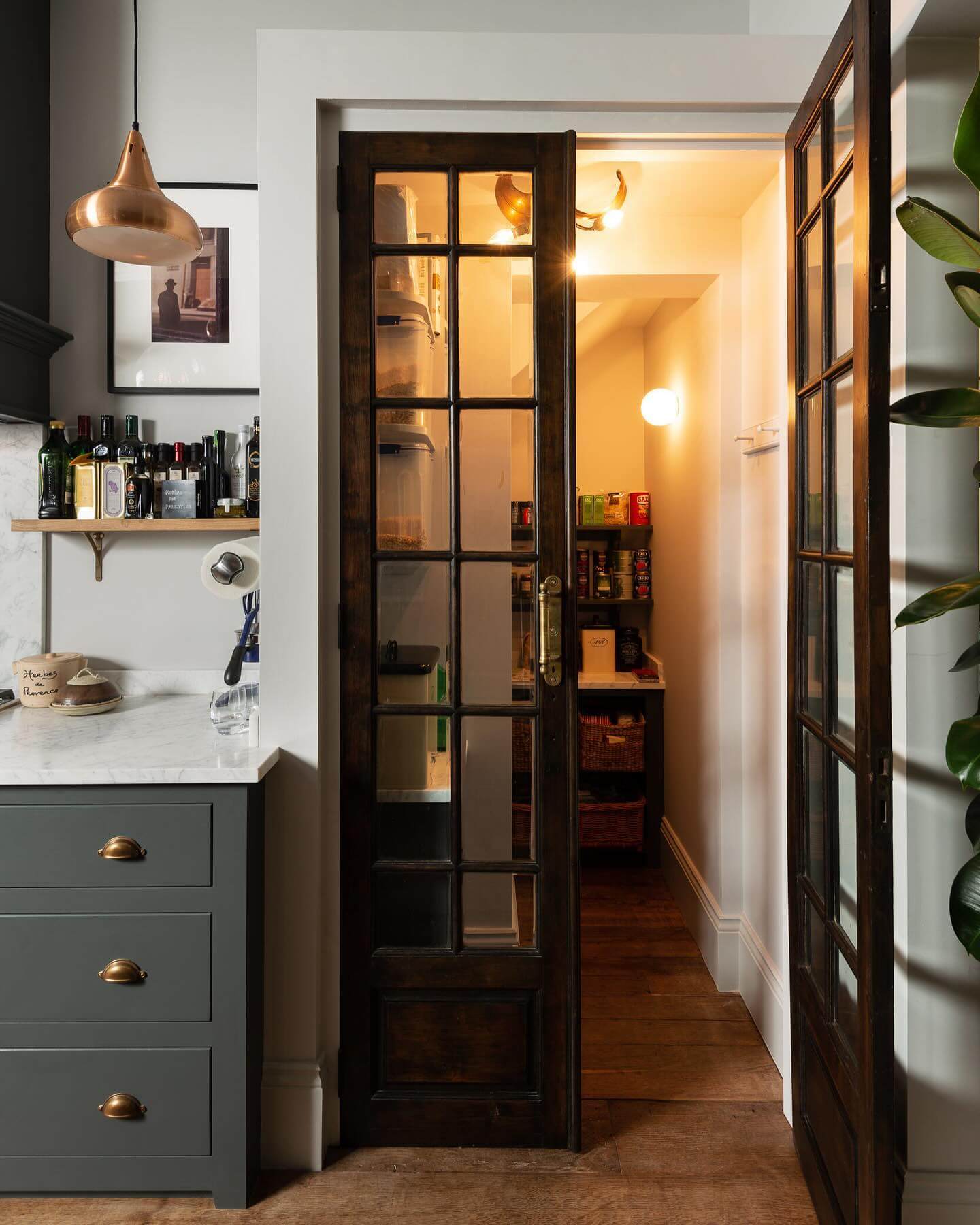 Glass-paneled doors reveal a narrow pantry lined with shelves