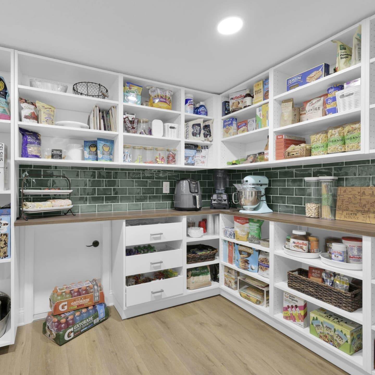 Deep green tile backsplash adds a rich backdrop to pantry shelves