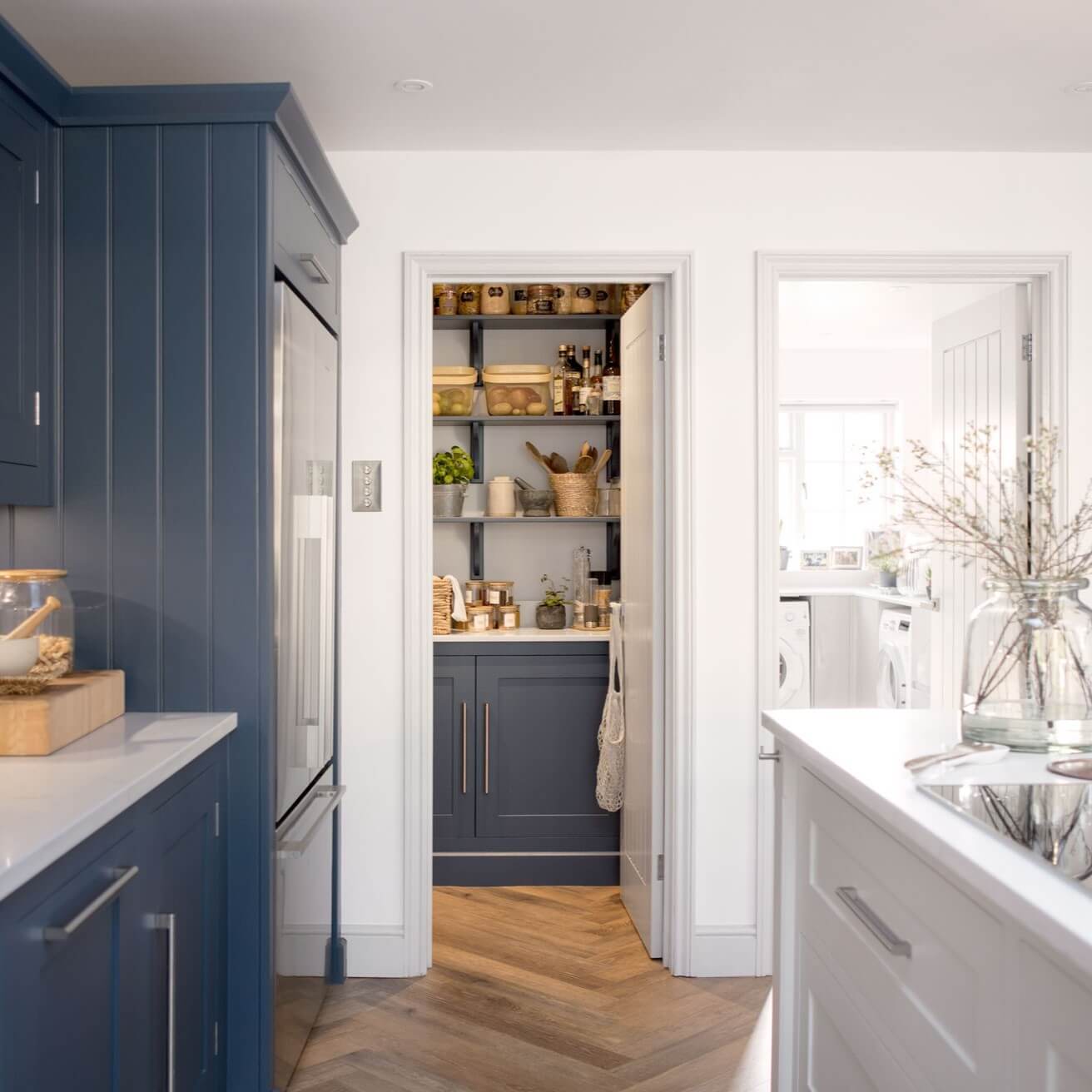 Deep blue cabinets ground the pantry's open shelving