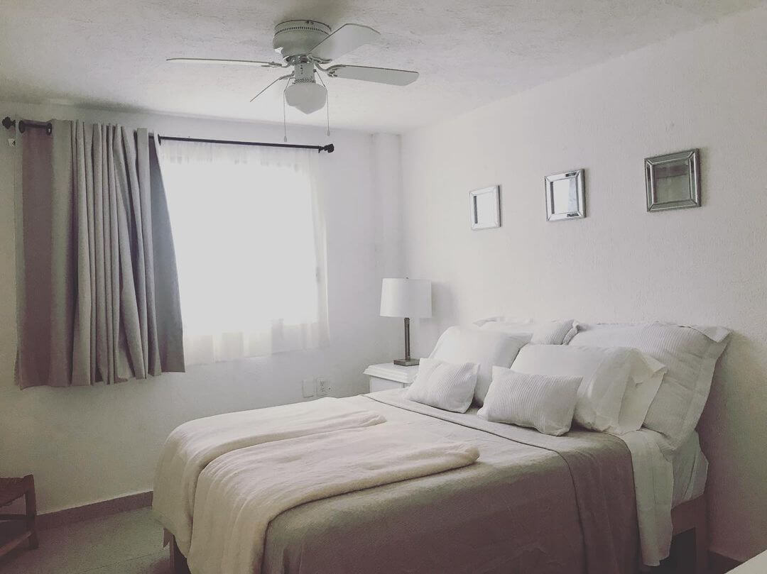 Framed Mirrors Add Subtle Shine Above a White Bed