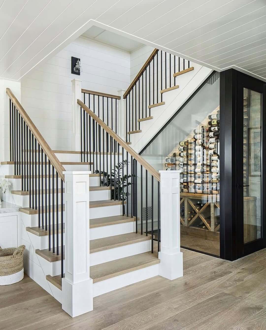 Glass-Enclosed Wine Cellar Creates Dramatic Staircase Backdrop