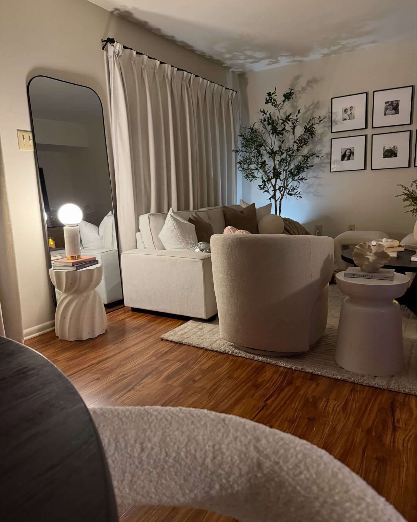 Sculptural Side Table Holds Lamp and Books Near Floor Mirror