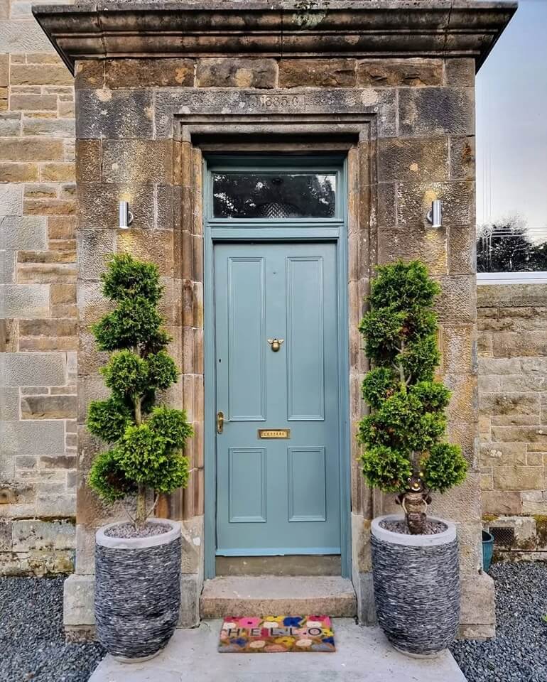 Soft Blue Door With Bee Knocker and Topiary Trees
