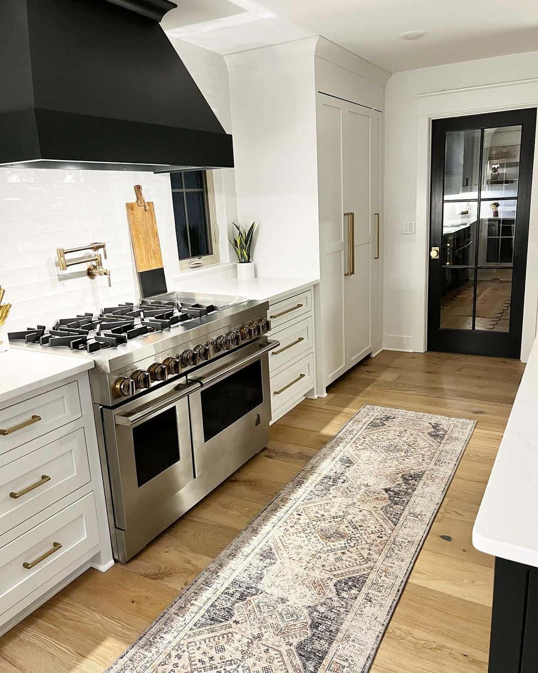 Brass Bar Pulls Complement White Drawers Next to a Black Range Hood