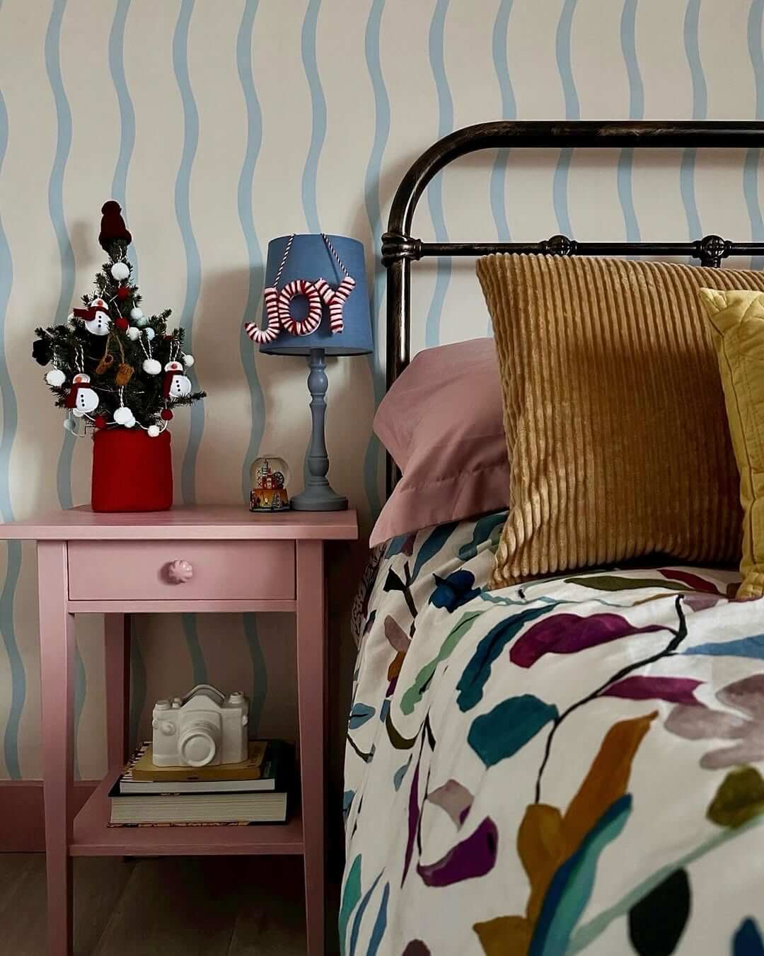 Pink Drawer Nightstand With Stacked Books and Camera Decor