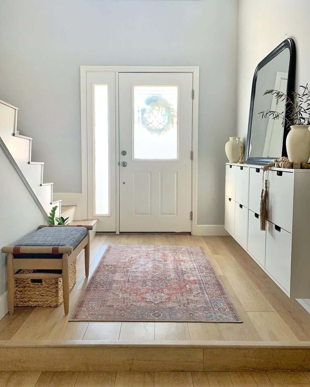 Black Framed Mirror Above White Storage Cabinets