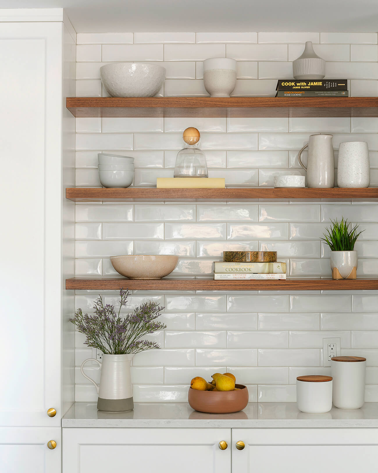 Stacked cookbooks add height and texture to wooden shelves