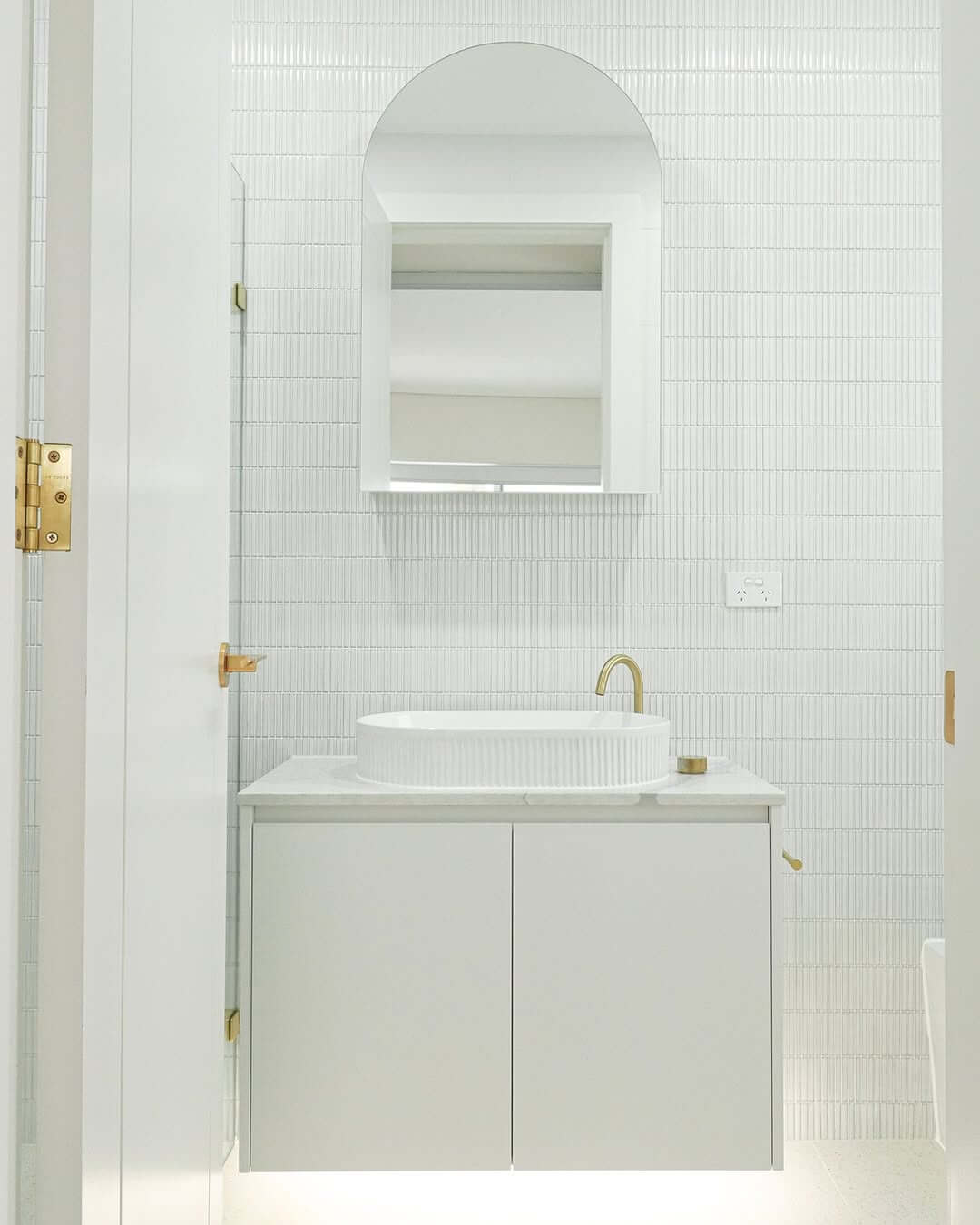 Arched Mirror Frames a Ribbed Vessel Sink