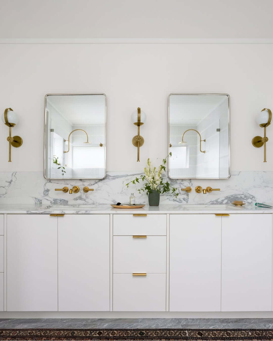 Rounded Mirrors Frame a White Vanity With Brass Faucets